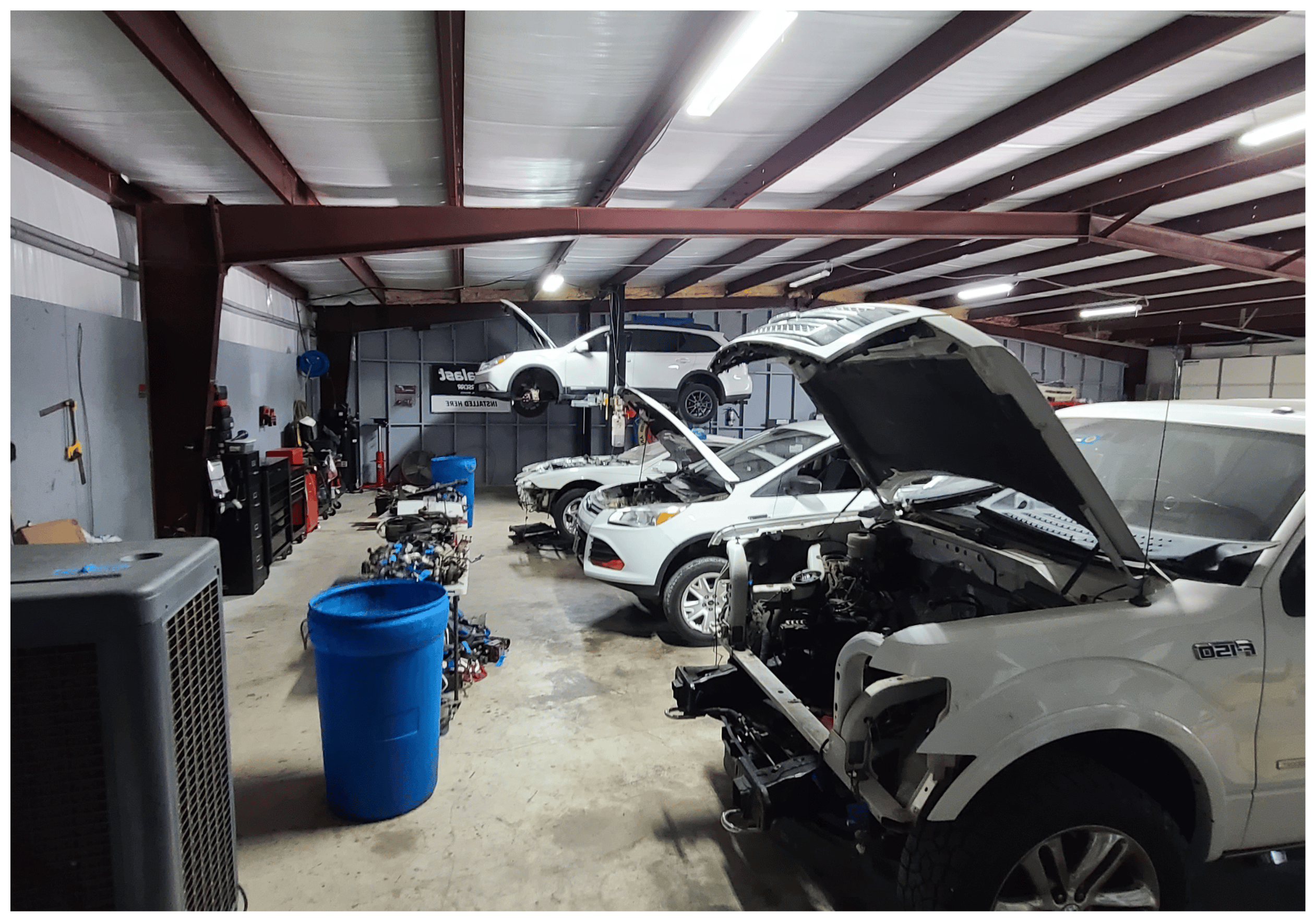 Inside Brittni's Automotive shop. Four white cars ar eline on the right side for auto repairs, with equipment found on the left side.