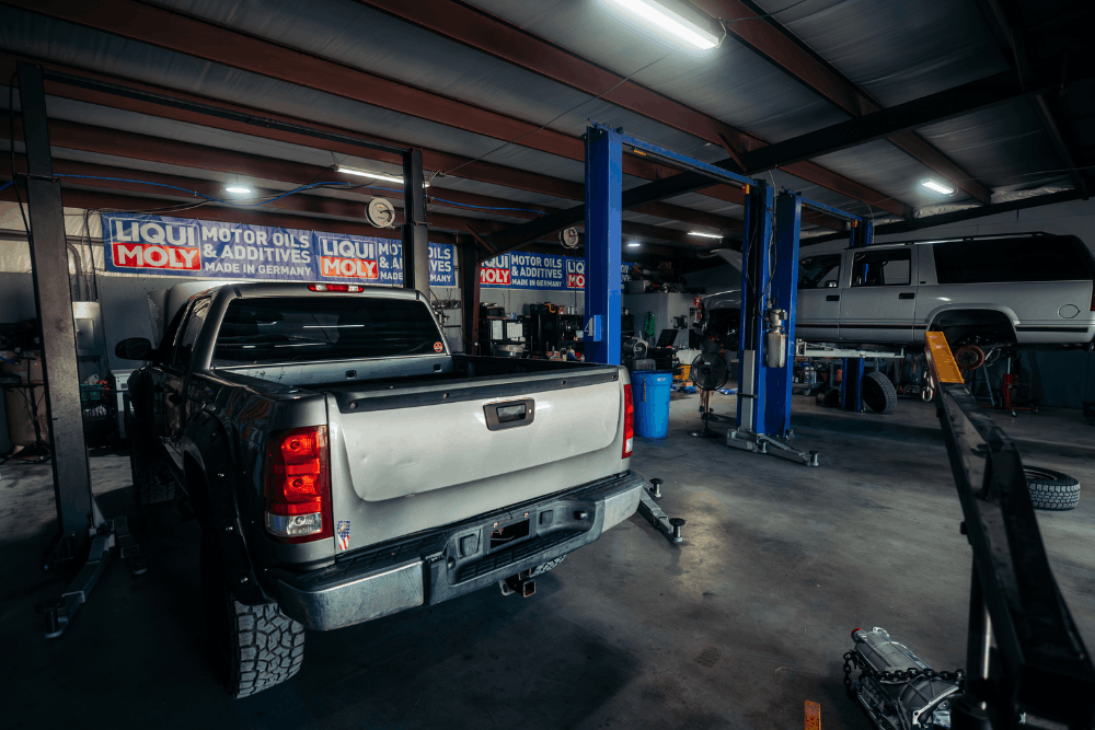 Fleet repair services in Haslet, TX at Brittni's Automotive Repair. Image of pickup trucks inside the service shop, with one vehicle raised on a lift for maintenance.